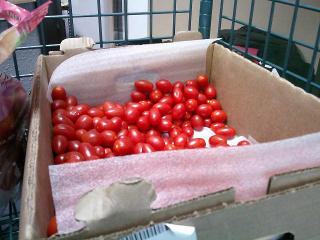 Banana box bottom full of grape tomatoes on a shelf.
